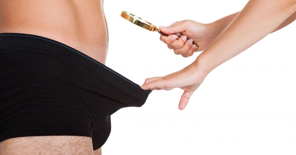 Një vajzë shikon përmes një gote zmadhuese në një penis të vogël